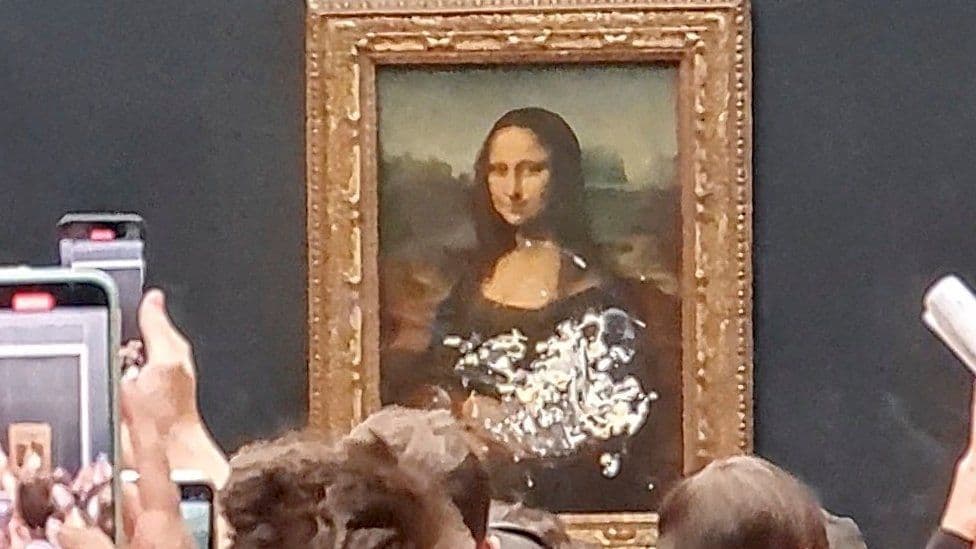 Burri i veshur si femër hedh tortë mbi pikturën e Mona Lisa: Mendoni për Tokën! (VIDEO)
